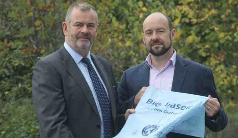 wo directors, Myles Thorn and Adam Thorn, from earth2earth and Thorn Environmental, respectively, stand outside showing new Bio Based Carbon Capture Sacks. They are in suits and are proudly presenting their new innovation: Bio-based Carbon Captured light blue sacks
